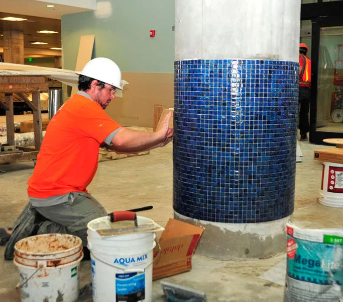 Pro-Floors Plus installer setting blue mosaic tile on a column